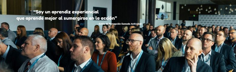 Un grupo de personas asistiendo a un seminario de negocios y la cita: 'Soy un aprendiz experiencial que aprende mejor al sumergirme en la acción', atribuida a una persona con el Estilo de Percepción Actividad.