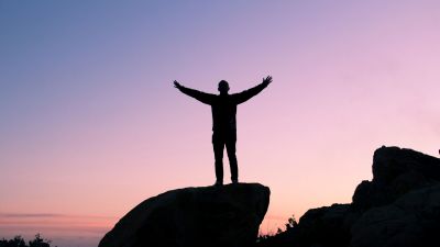 Picture of a man on top of a mountain celebrating his achievement